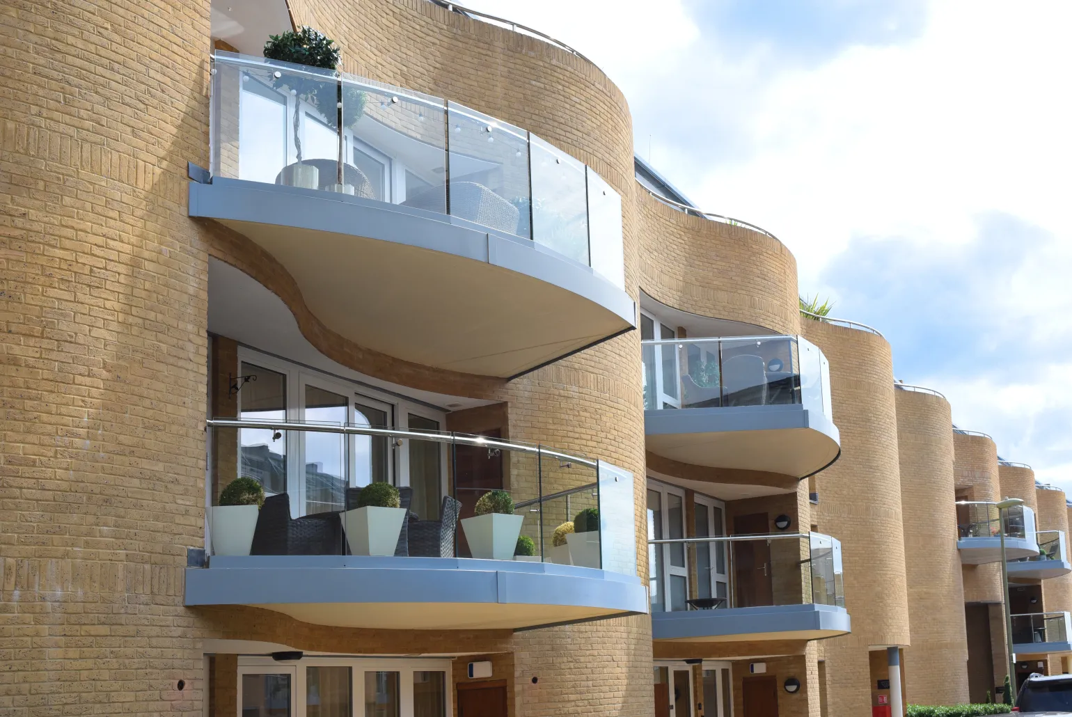 What is a Frameless Glass Balustrade?
There are many different railing systems available for home and commercial use, but many of these options obstruct one’s views to a certain extent. Frameless glass balustrades solve this challenge by offering robust railing without any visible frames. These balustrades are made from panels of tempered glass, offering sleek modern looks and unobstructed views along with superior safety and robust designs.
A quality frameless glass balustrade is made from thick, durable tempered glass that will shatter into tiny, blunt fragments if damaged. This feature reduces the risk of injury and ensures compliance with modern building safety regulations. Their frameless design boasts a clean look, making spaces feel more open without compromising on safety. Instead of frames, these balustrades use corrosion-resistant aluminium or stainless steel clamps and base channels to secure each panel.